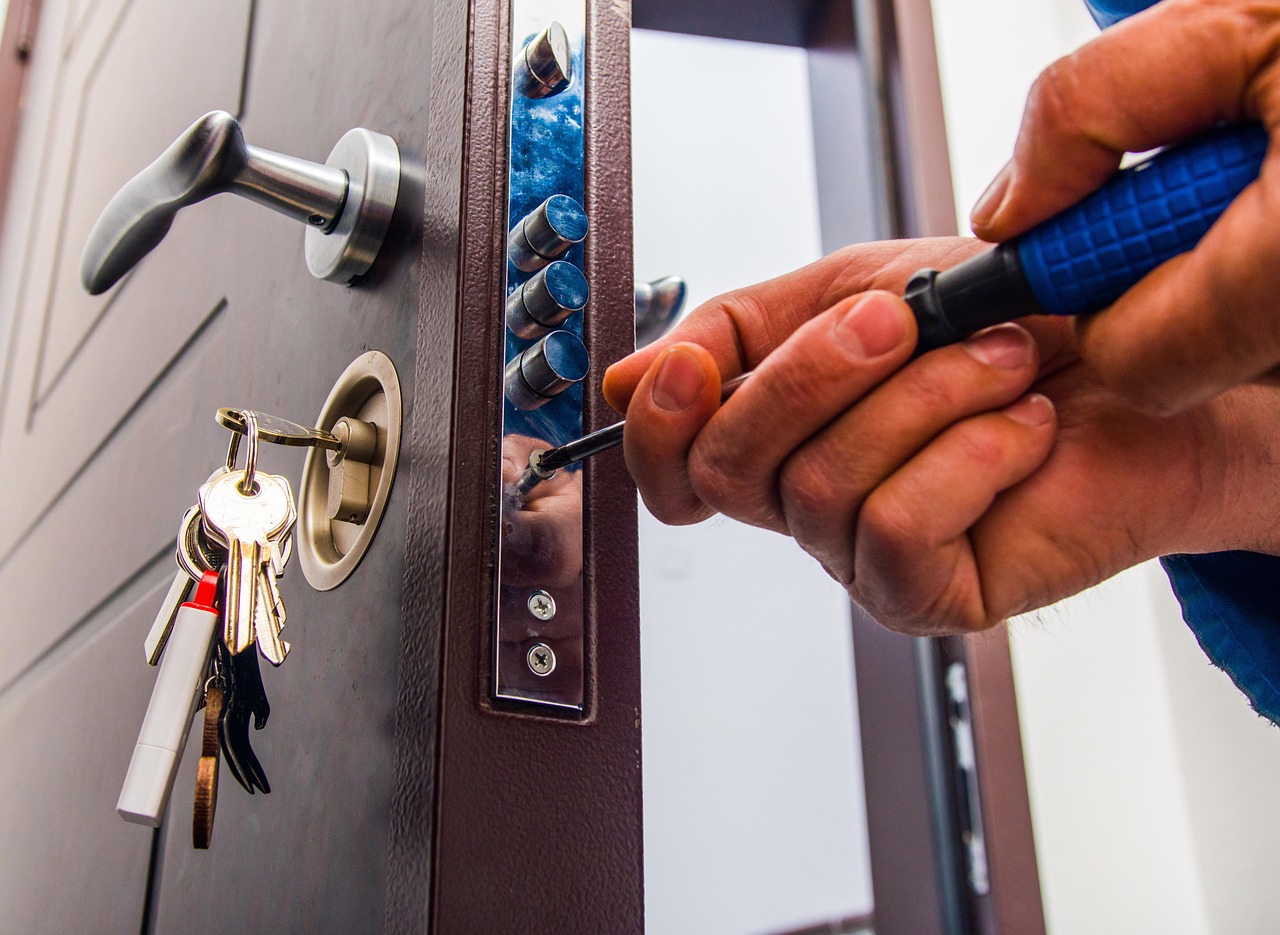 Gros plan sur un serrurier intervenant sur la serrure multipoints d’une porte